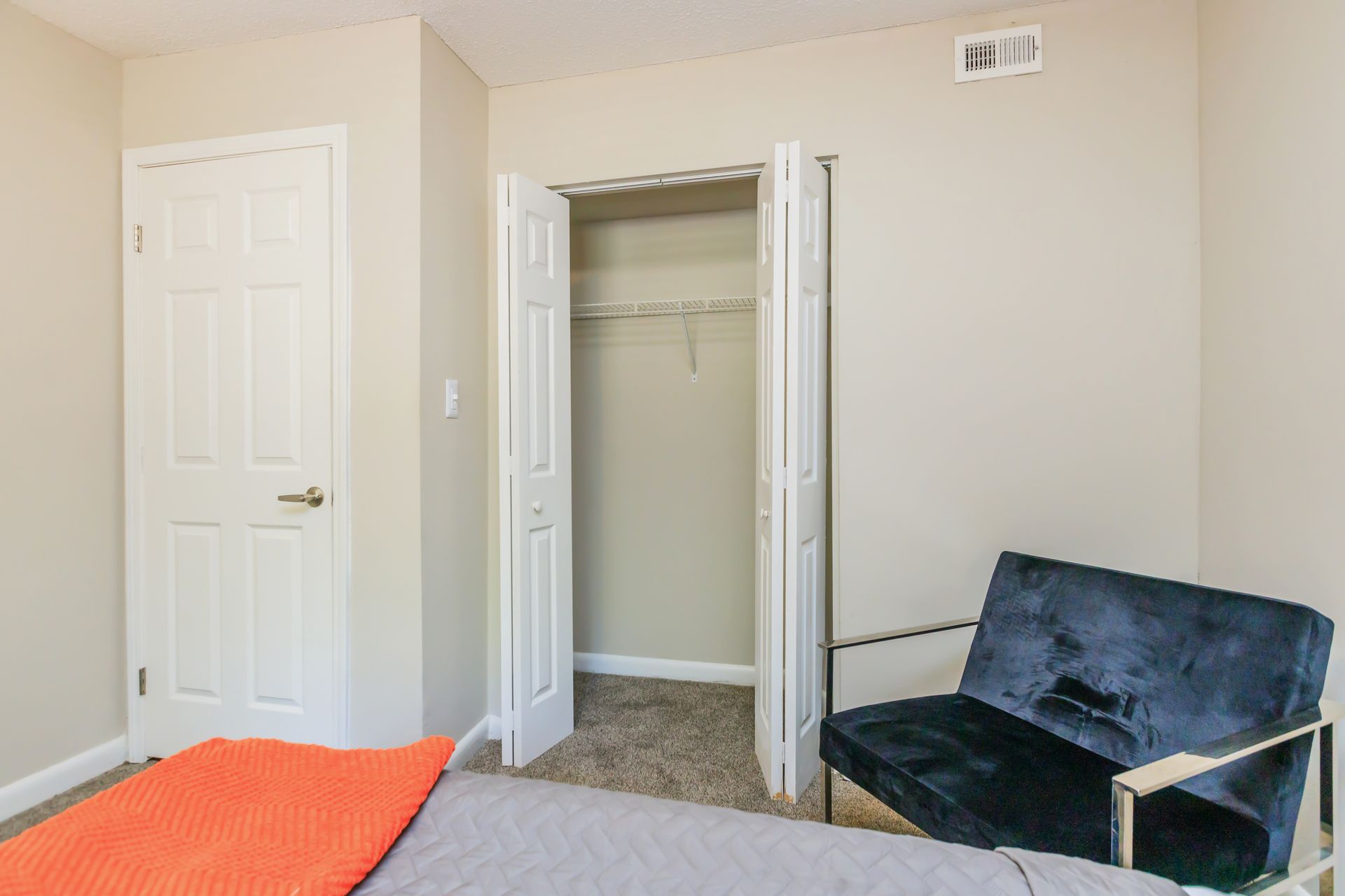 A bedroom with a bed , chair and closet.