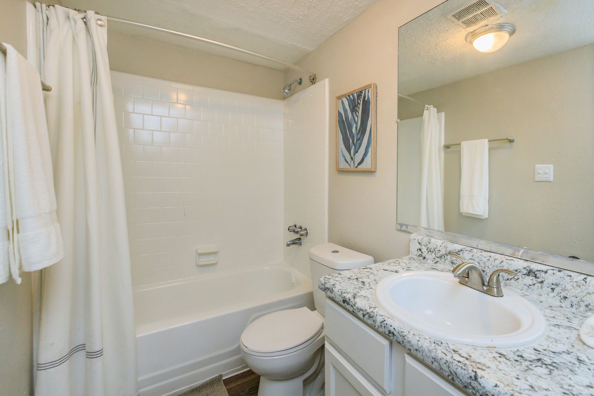A bathroom with a toilet , sink , bathtub and mirror.