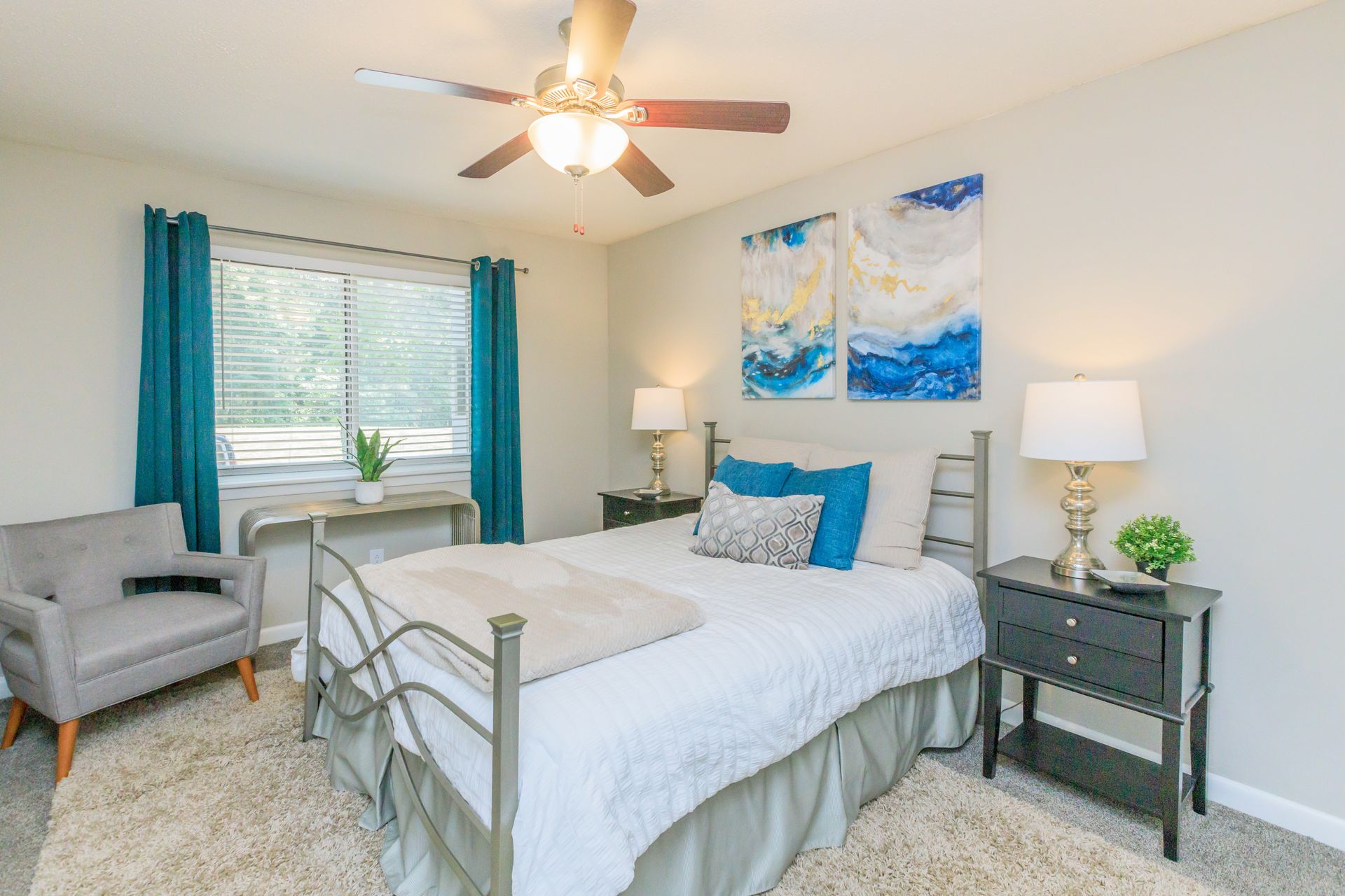 A bedroom with a bed , nightstand , chair and ceiling fan.