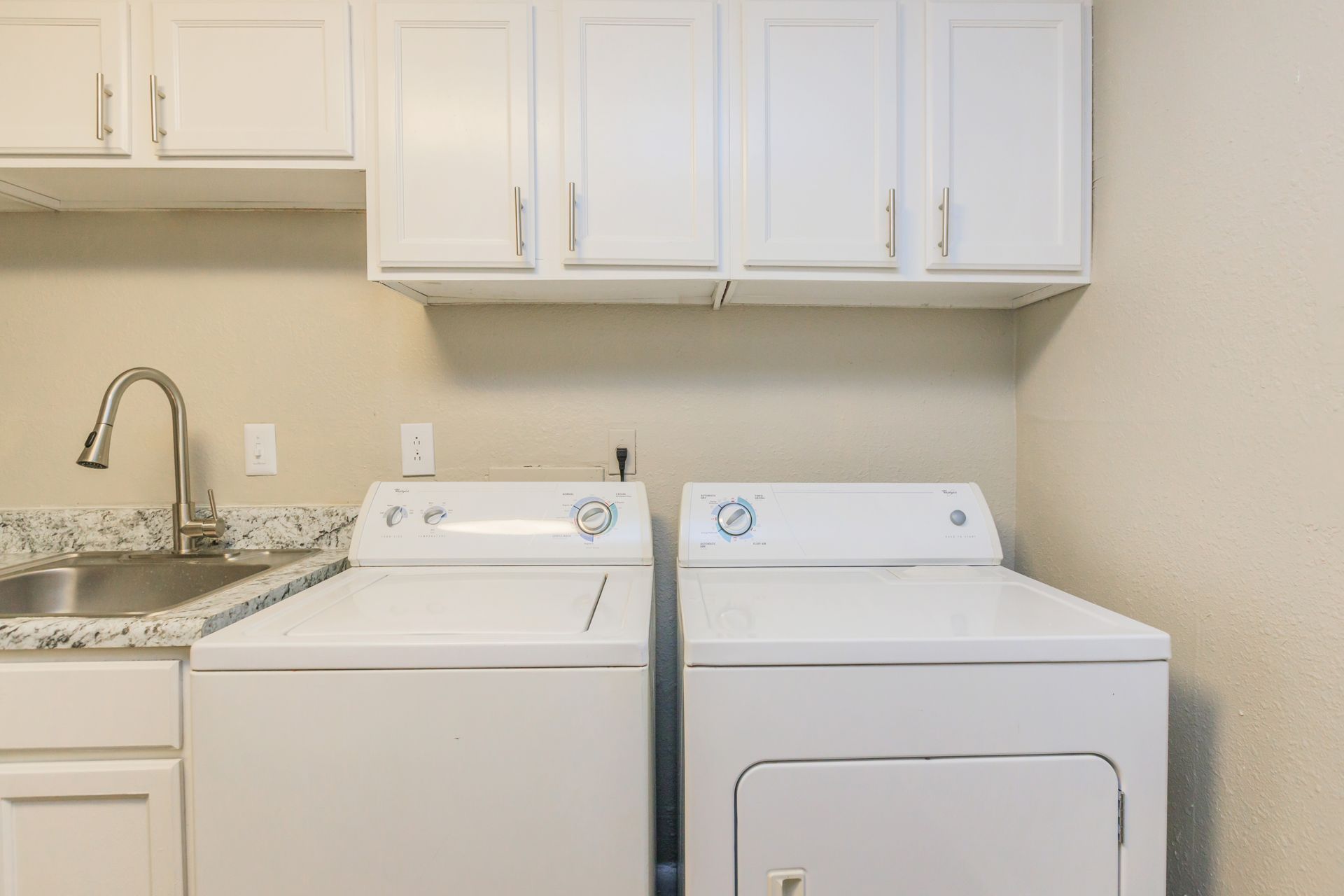 A laundry room with a washer and dryer and a sink.
