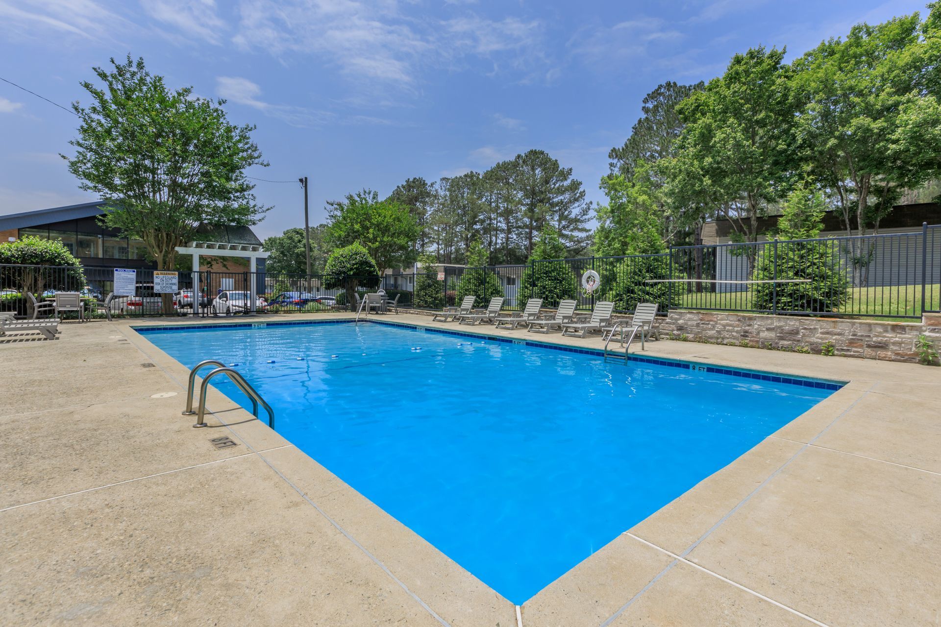 A large swimming pool surrounded by chairs and trees