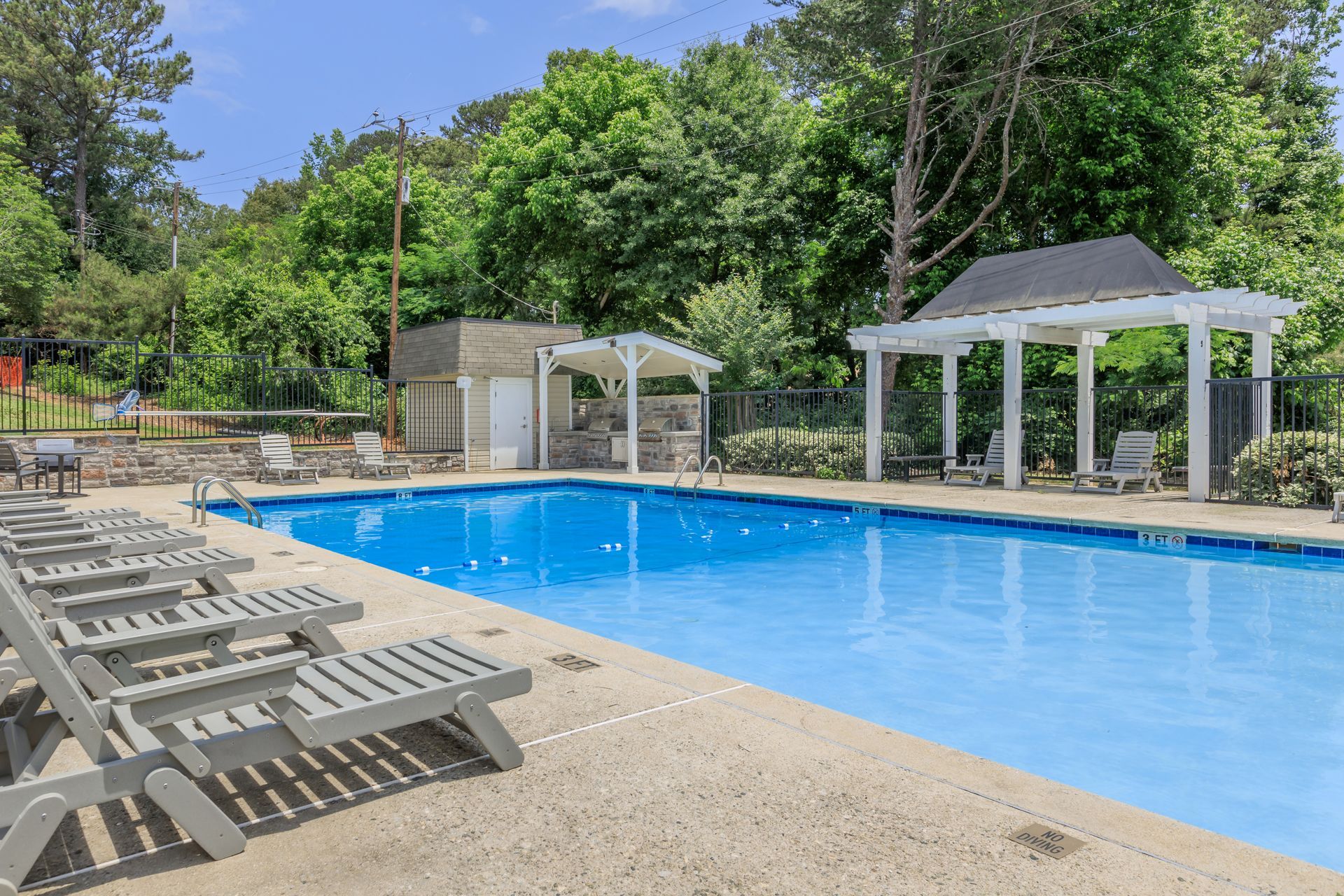 A large swimming pool surrounded by chairs and trees.