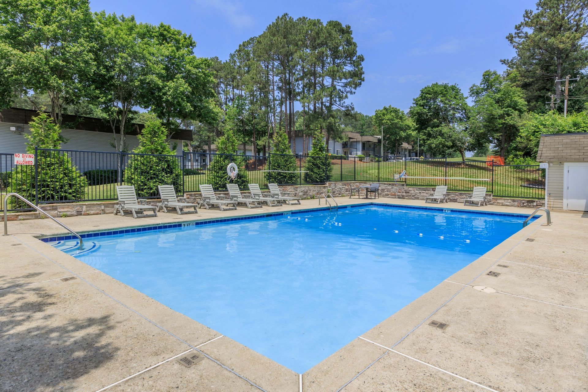A large swimming pool surrounded by chairs and trees