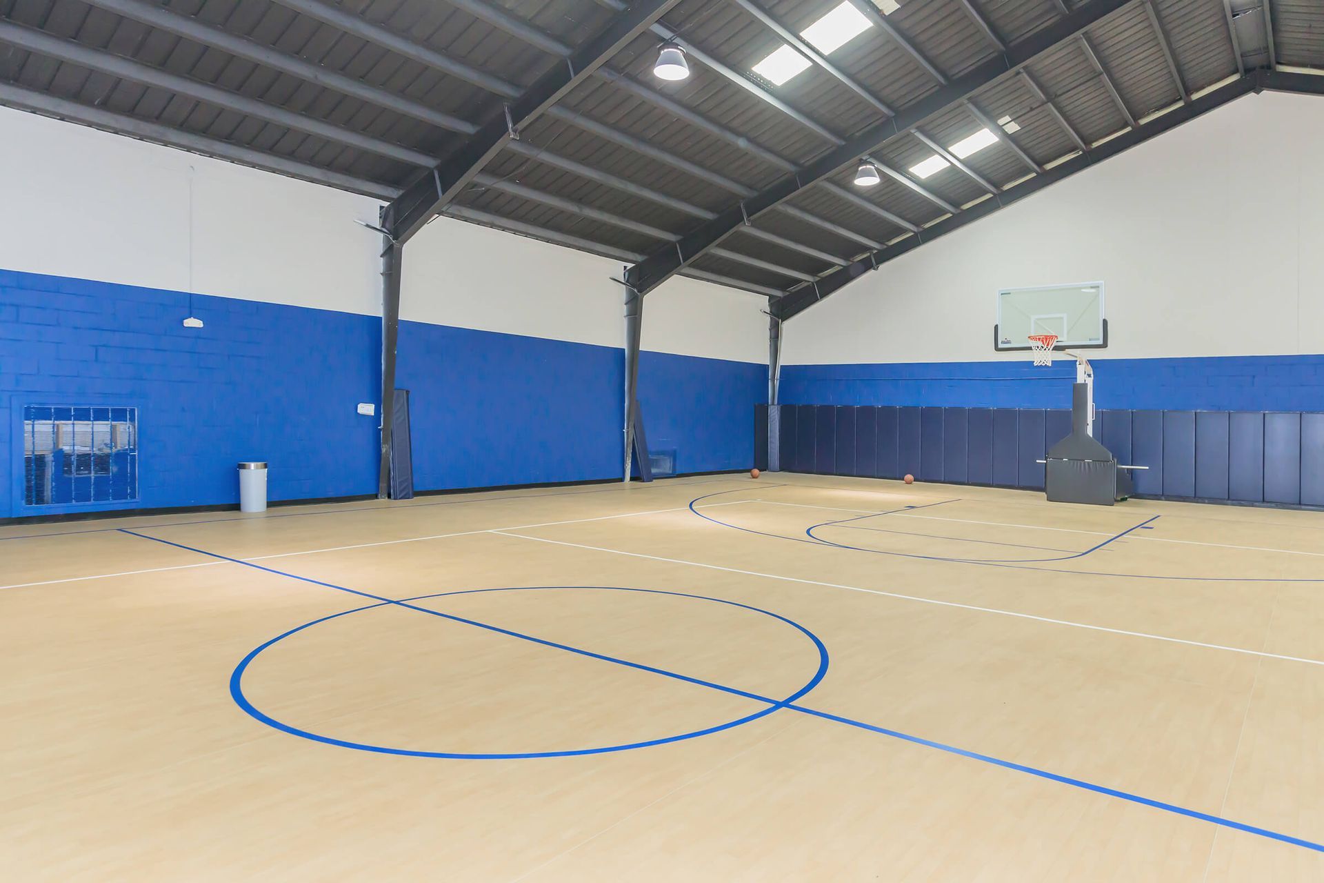 A large indoor basketball court with blue walls and a basketball hoop.