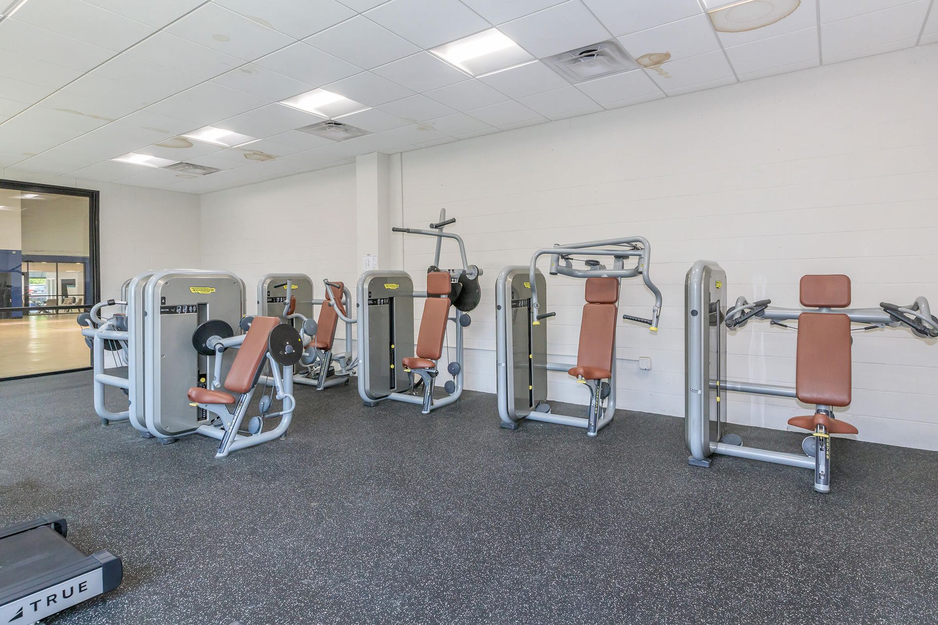 A gym filled with lots of exercise equipment and a treadmill.
