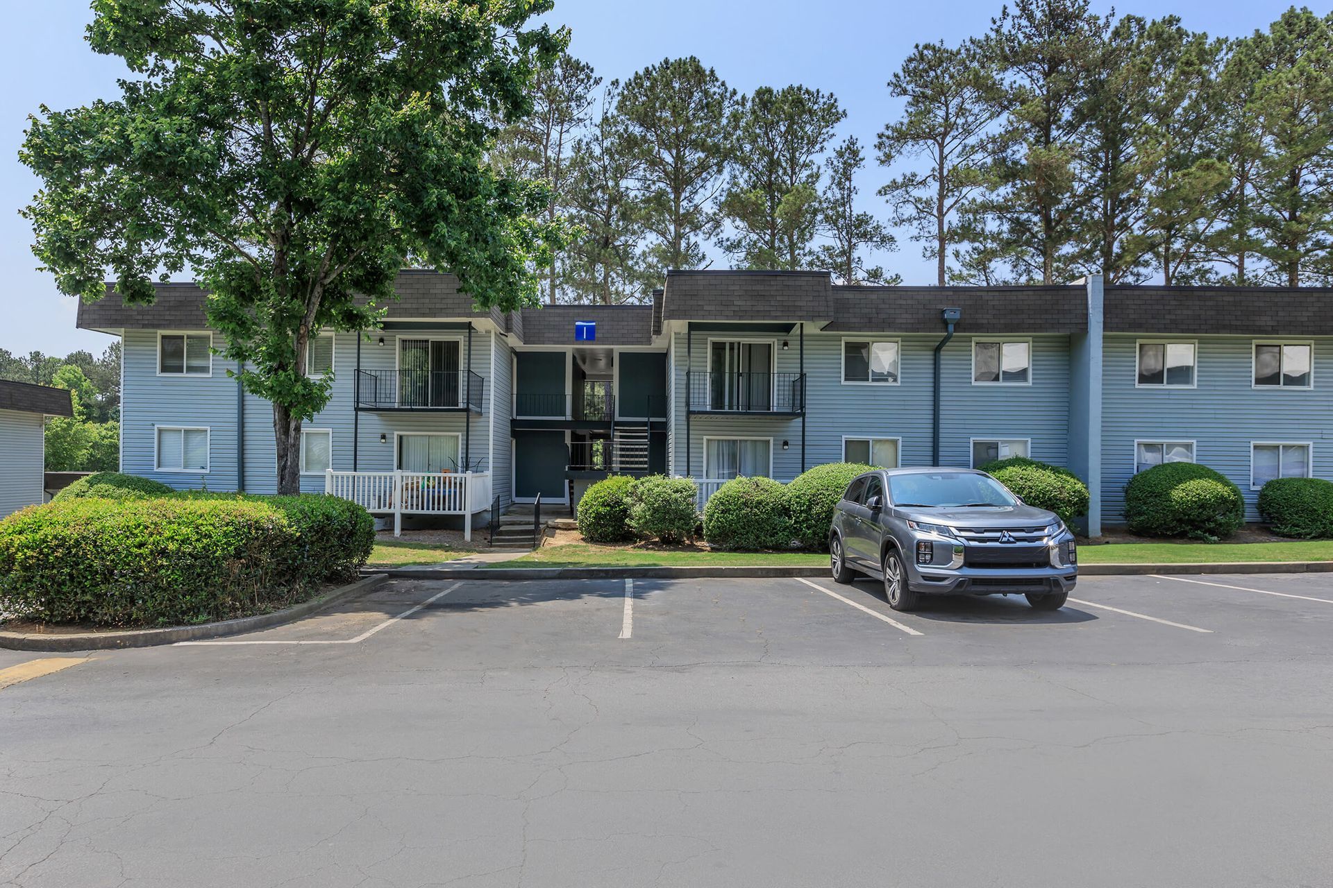 A car is parked in front of a blue apartment building.