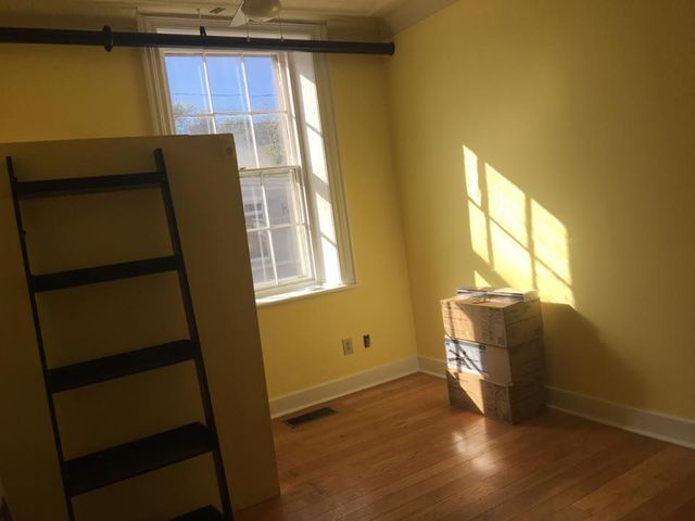 An empty room with a ladder and boxes on the floor