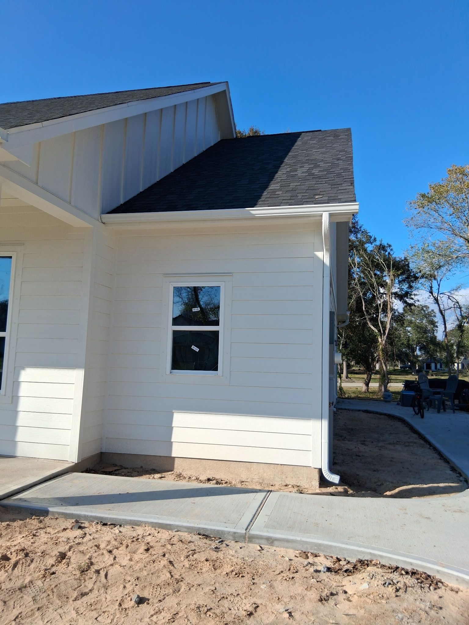 White building with black roof and one window under a clear blue sky.