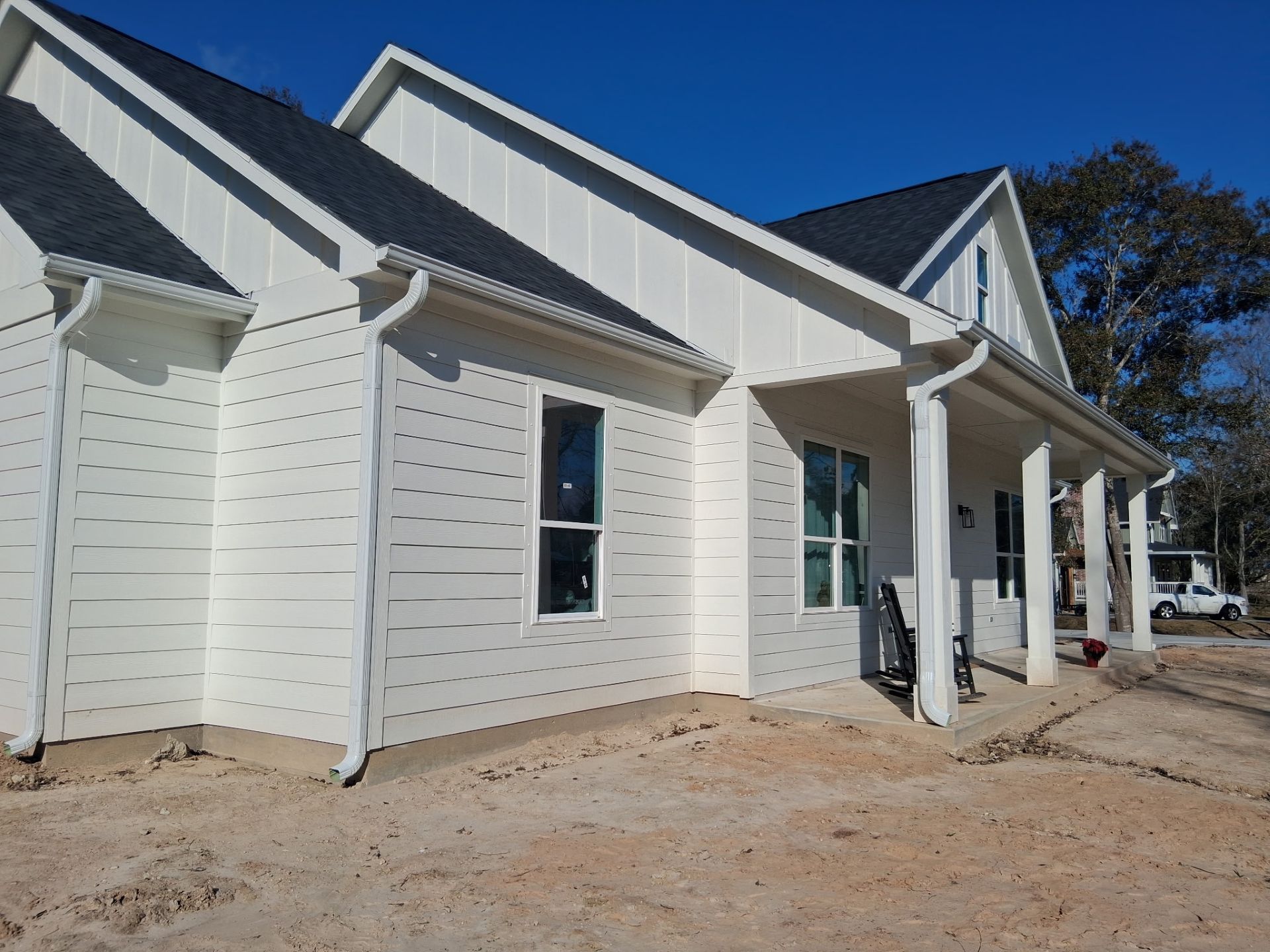 White house with black roof and white siding, clear blue sky.