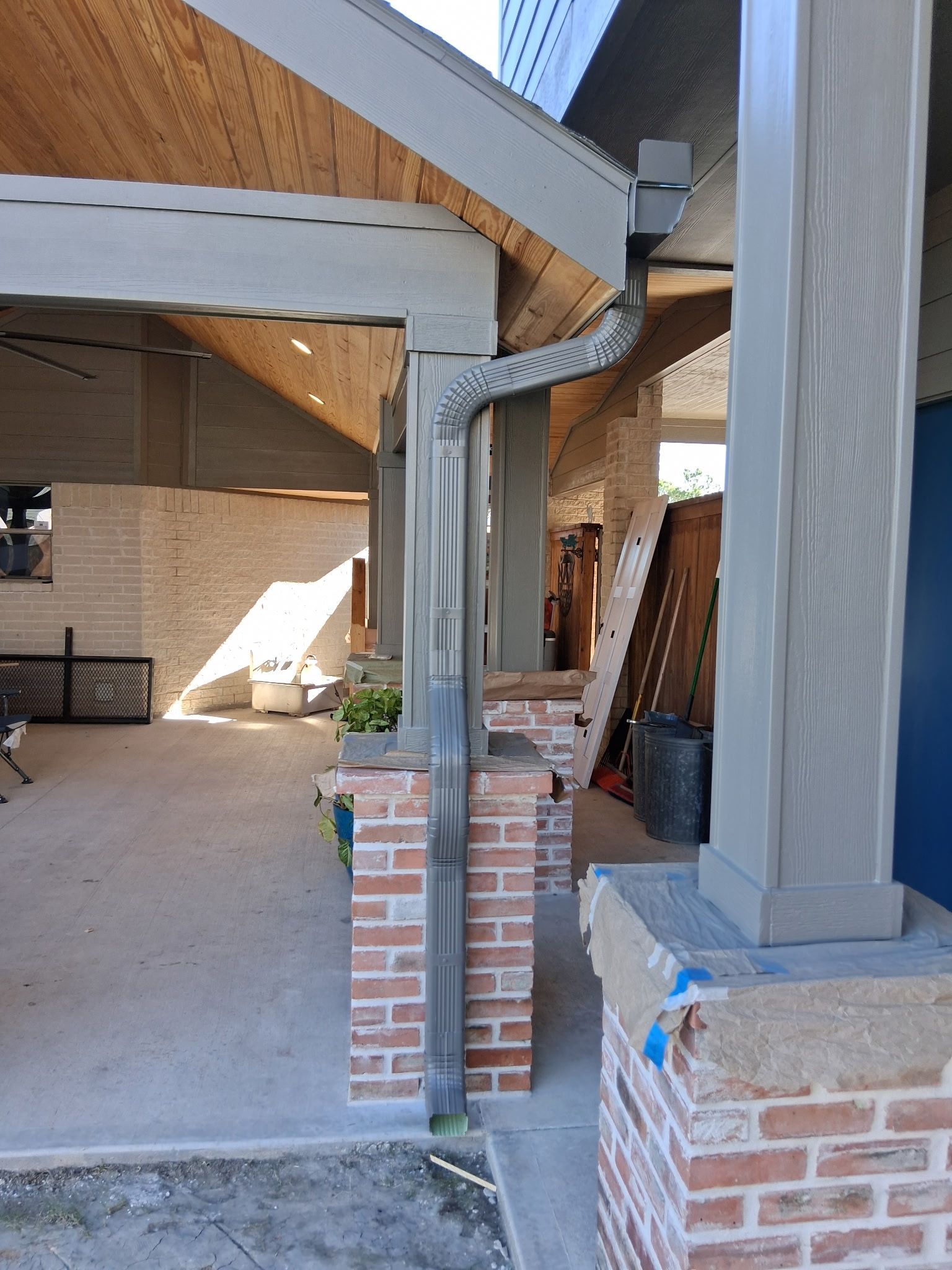 Brick and wood porch with a grey gutter and columns.