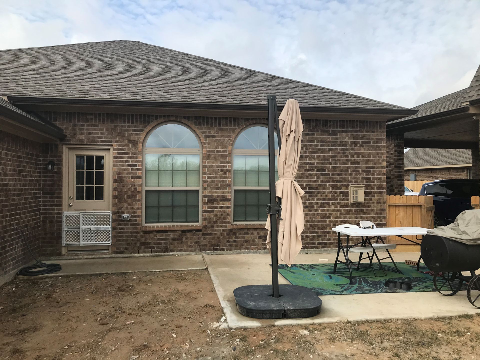 Brick house exterior with a patio, umbrella, and a table.