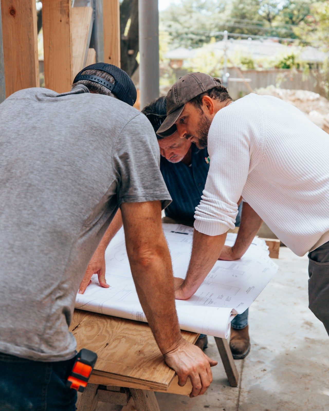 Three men are looking at a blueprint on a table.
