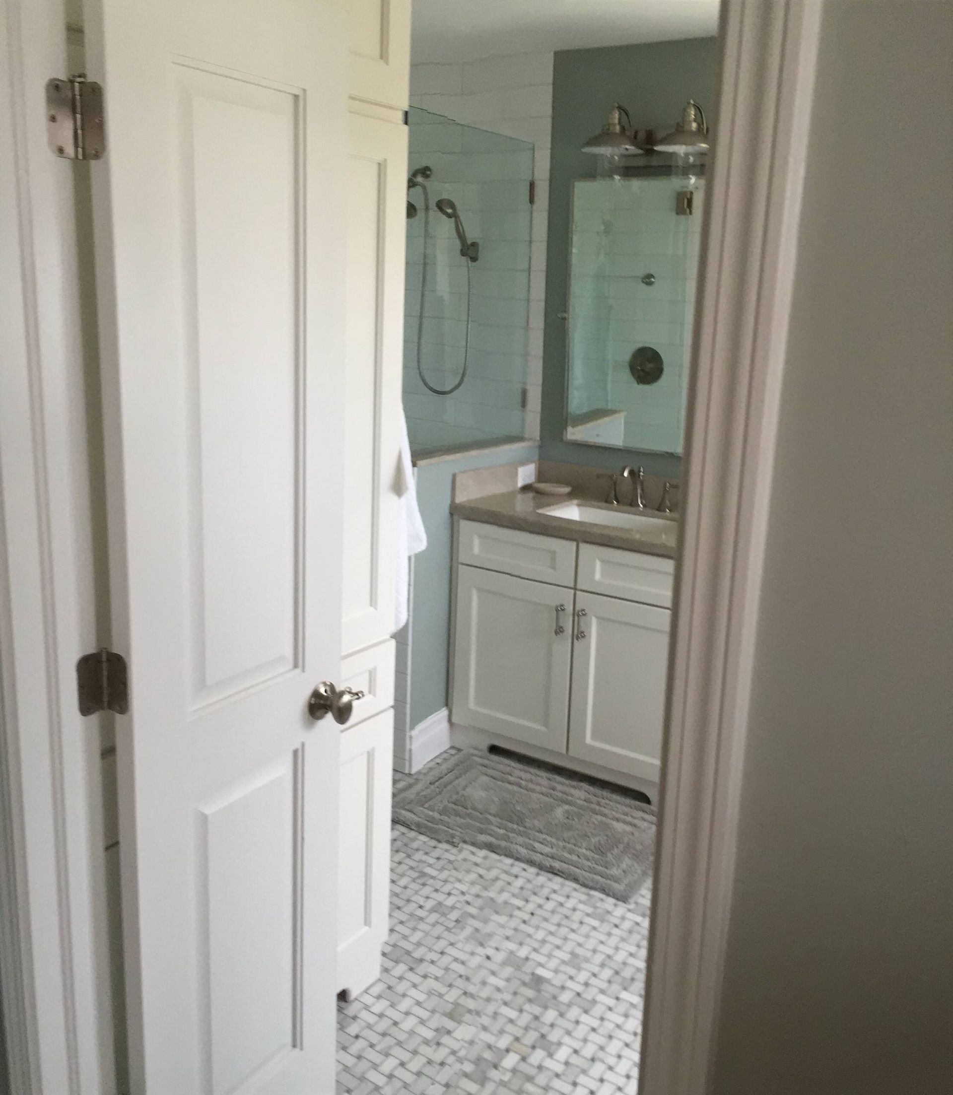 A bathroom with a sink , mirror and shower.