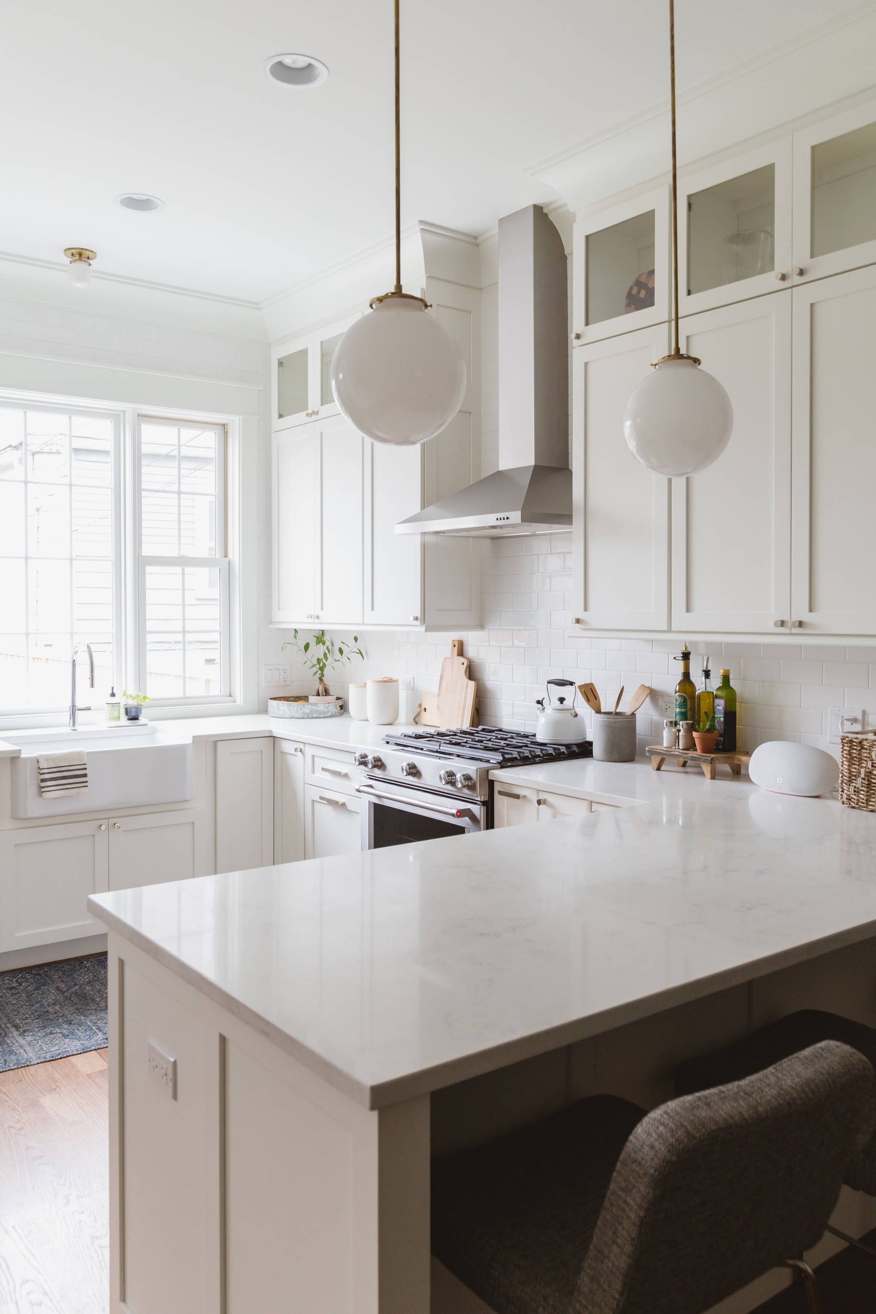 A kitchen with white cabinets , a stove , a sink , and a large island.