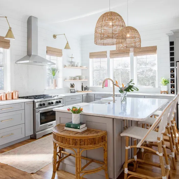 A kitchen with a large island , stools , a stove and a sink.