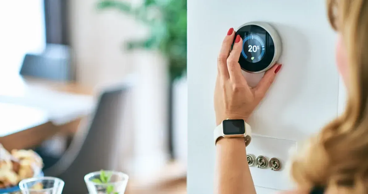 A woman is adjusting a smart thermostat in a living room.