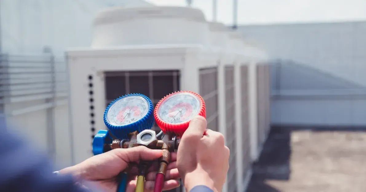 A person is holding two gauges in front of a building.
