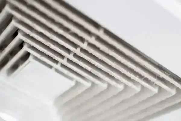 A close up of a ventilation grille on a ceiling.