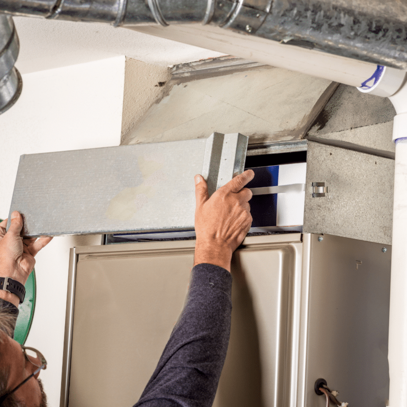 A man is working on an air conditioner with a screwdriver
