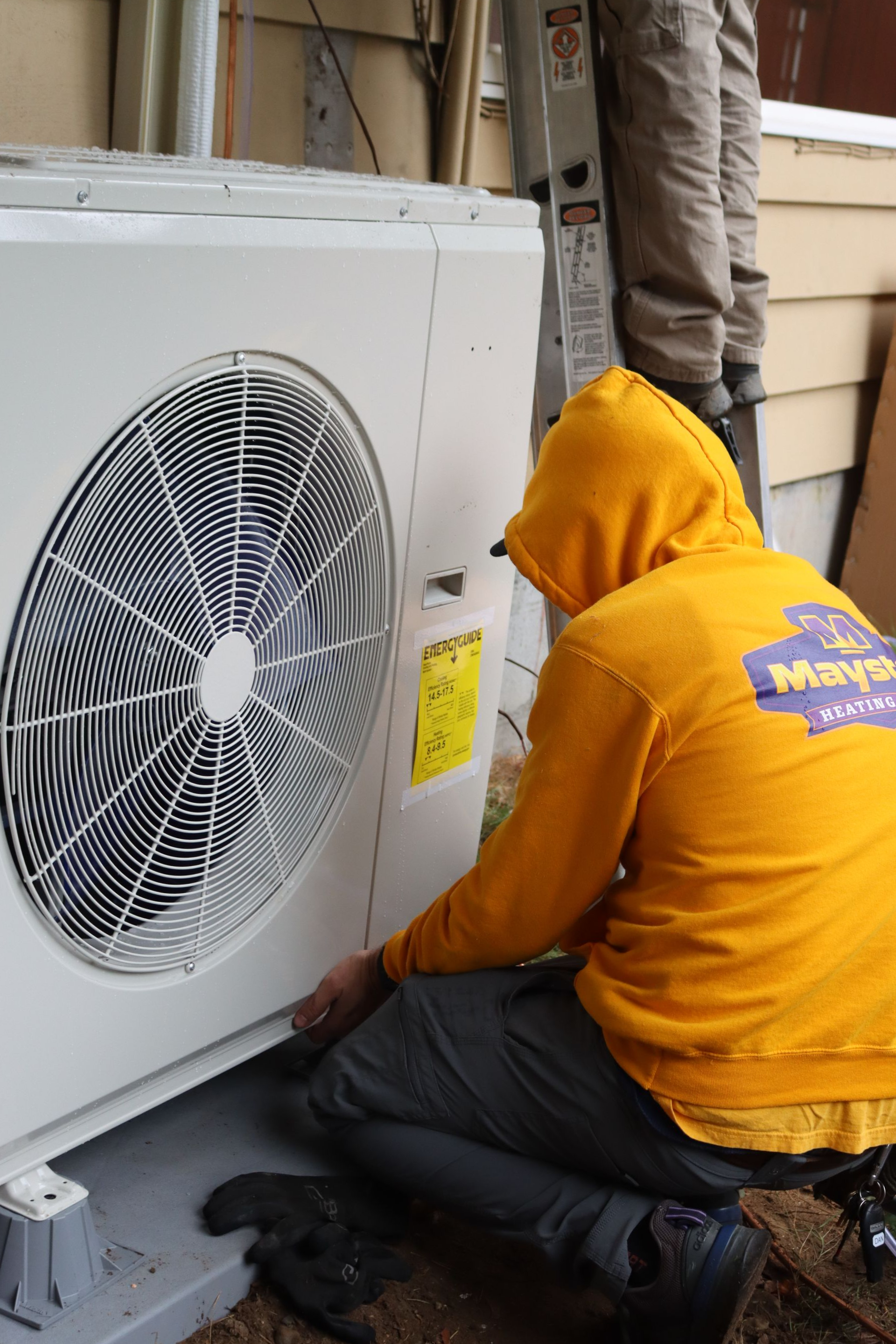 A man is installing a Bryant Heat Pump on the side of a house.