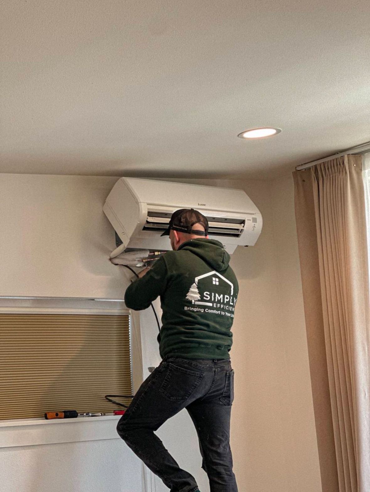 A man is working on an air conditioner in a living room.
