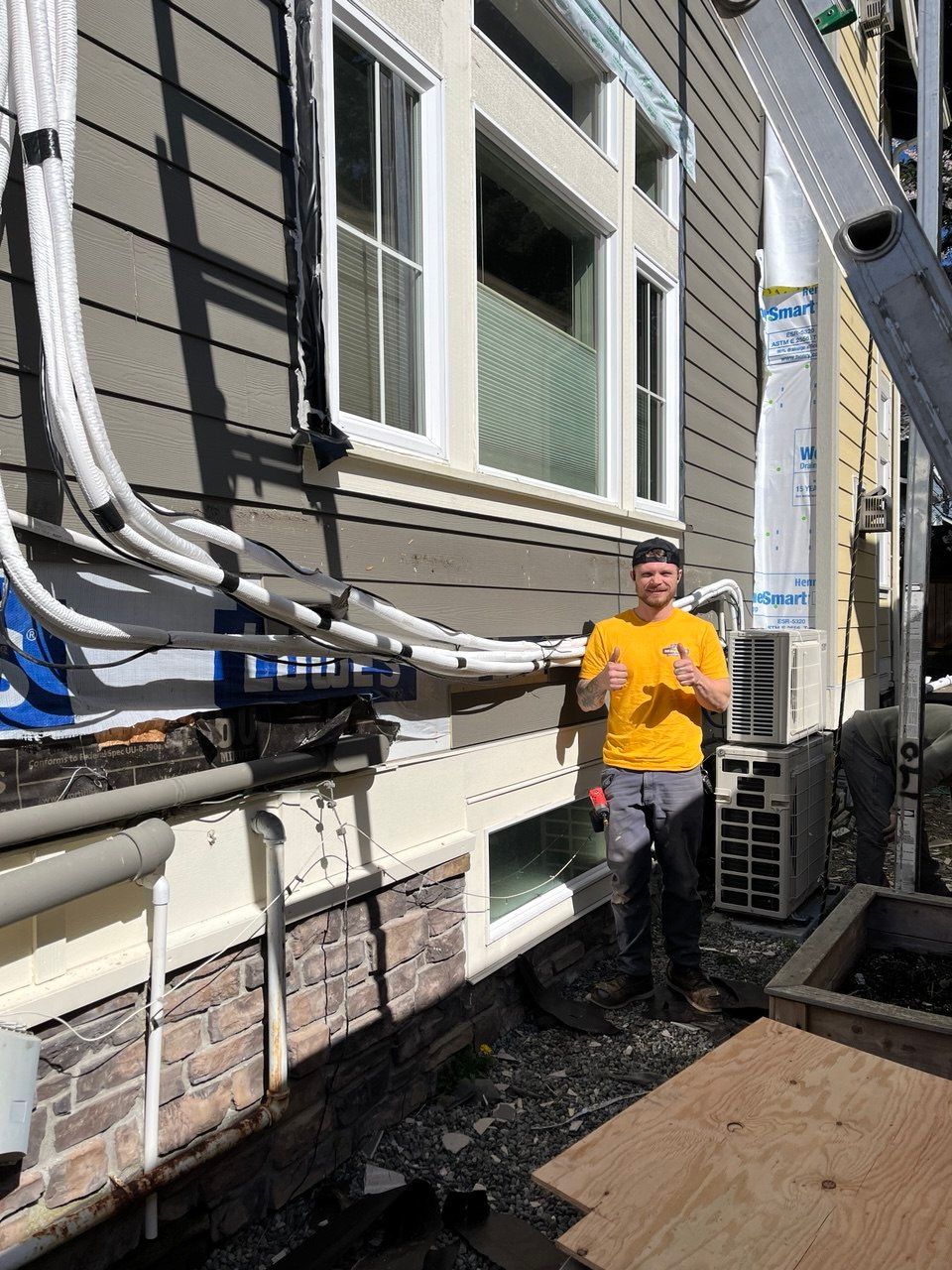 A man is working on an air conditioner with a hose.