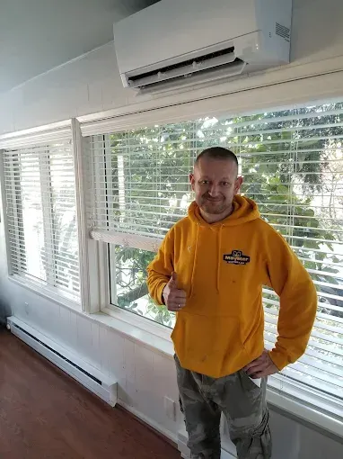 A man is working on an air conditioner in a living room.
