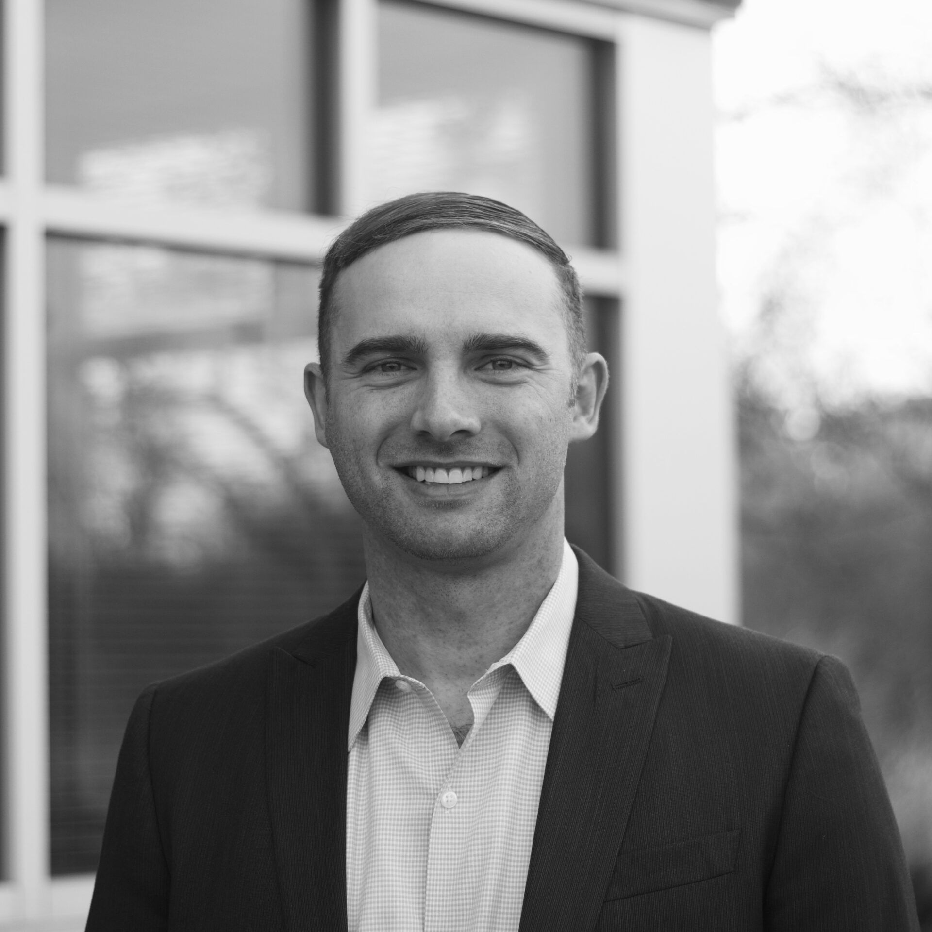 Man in a suit smiling in front of a window