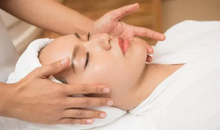 A woman is getting a facial massage at a spa.