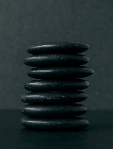 A stack of black rocks stacked on top of each other on a black surface.