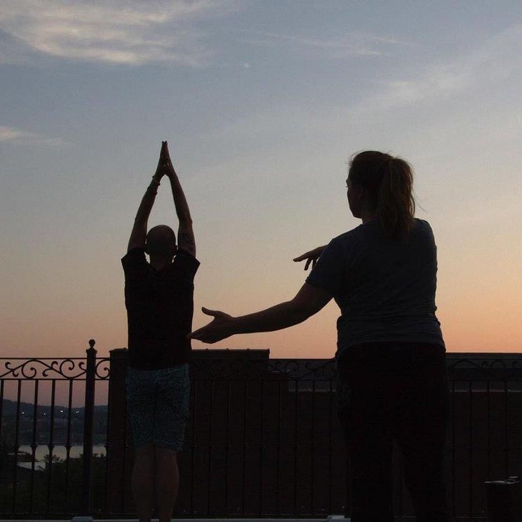 A man and a woman are doing yoga on a balcony at sunset