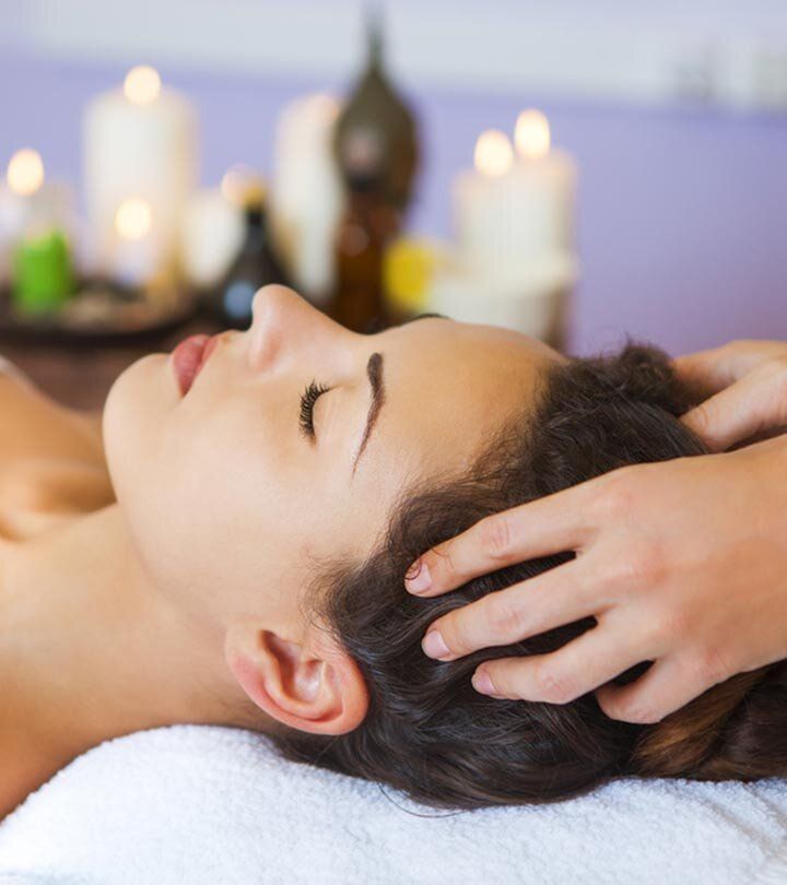 A woman is getting a head massage with candles in the background