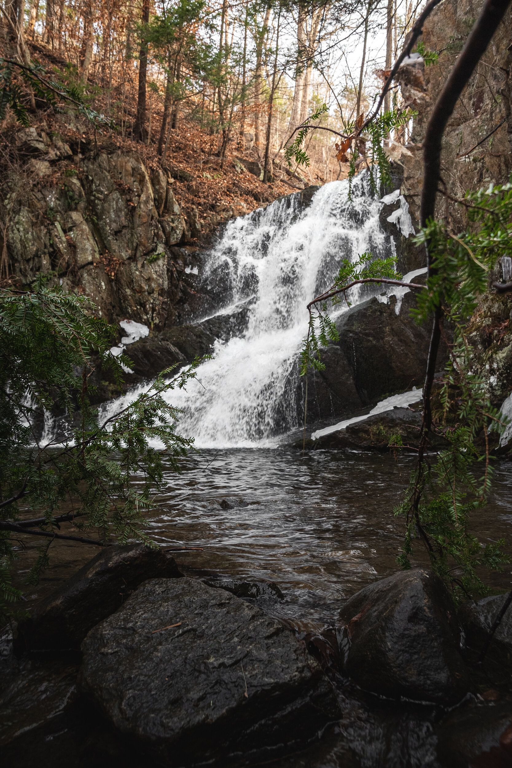 A waterfall is surrounded by rocks and trees in the woods.