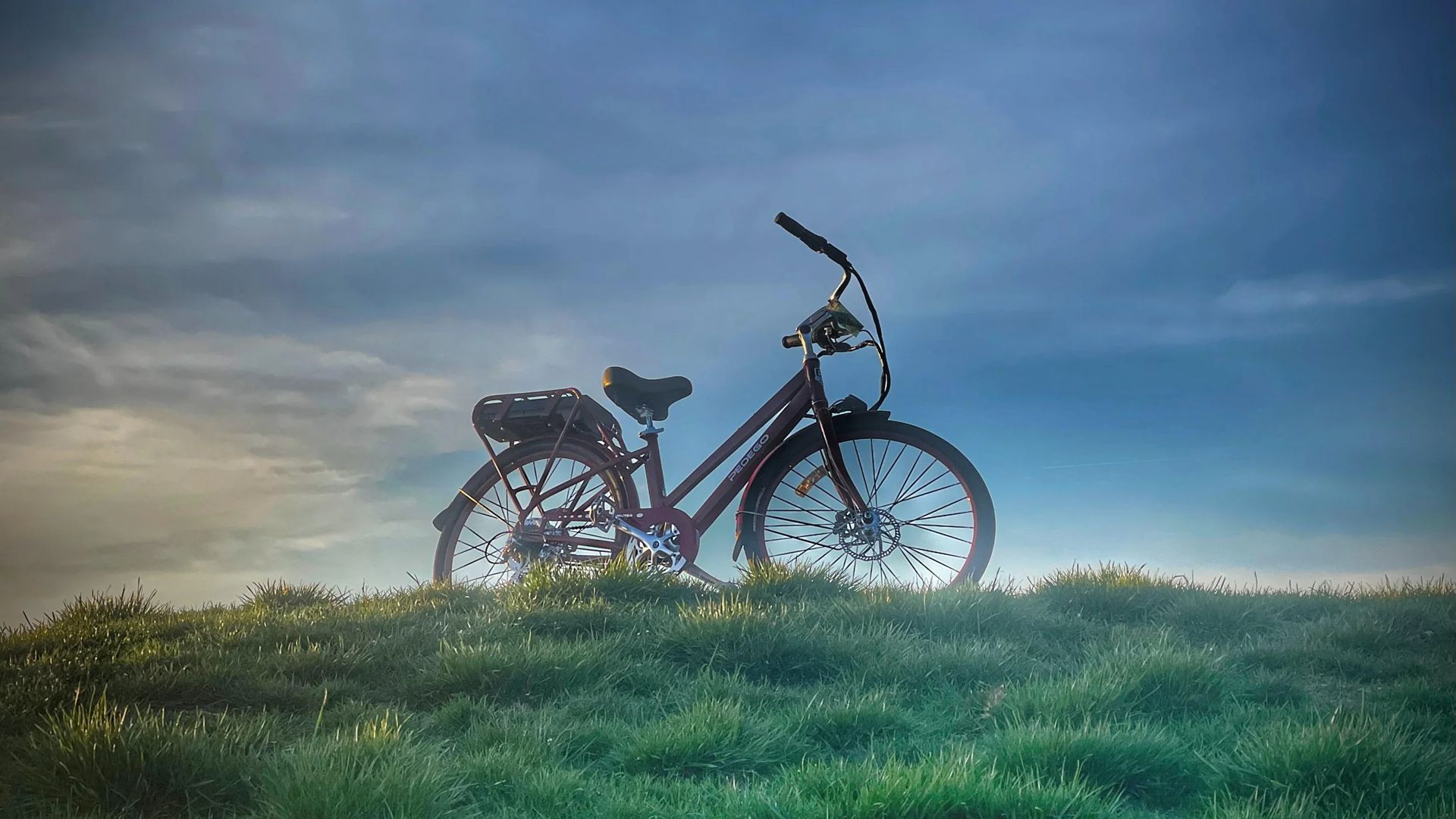 A bicycle is parked on top of a grassy hill.