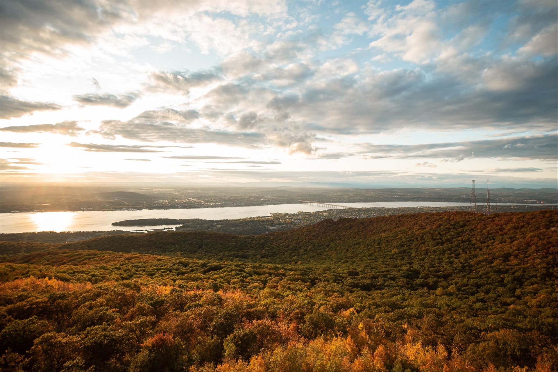 An aerial view of a lake surrounded by trees and a city at sunset.