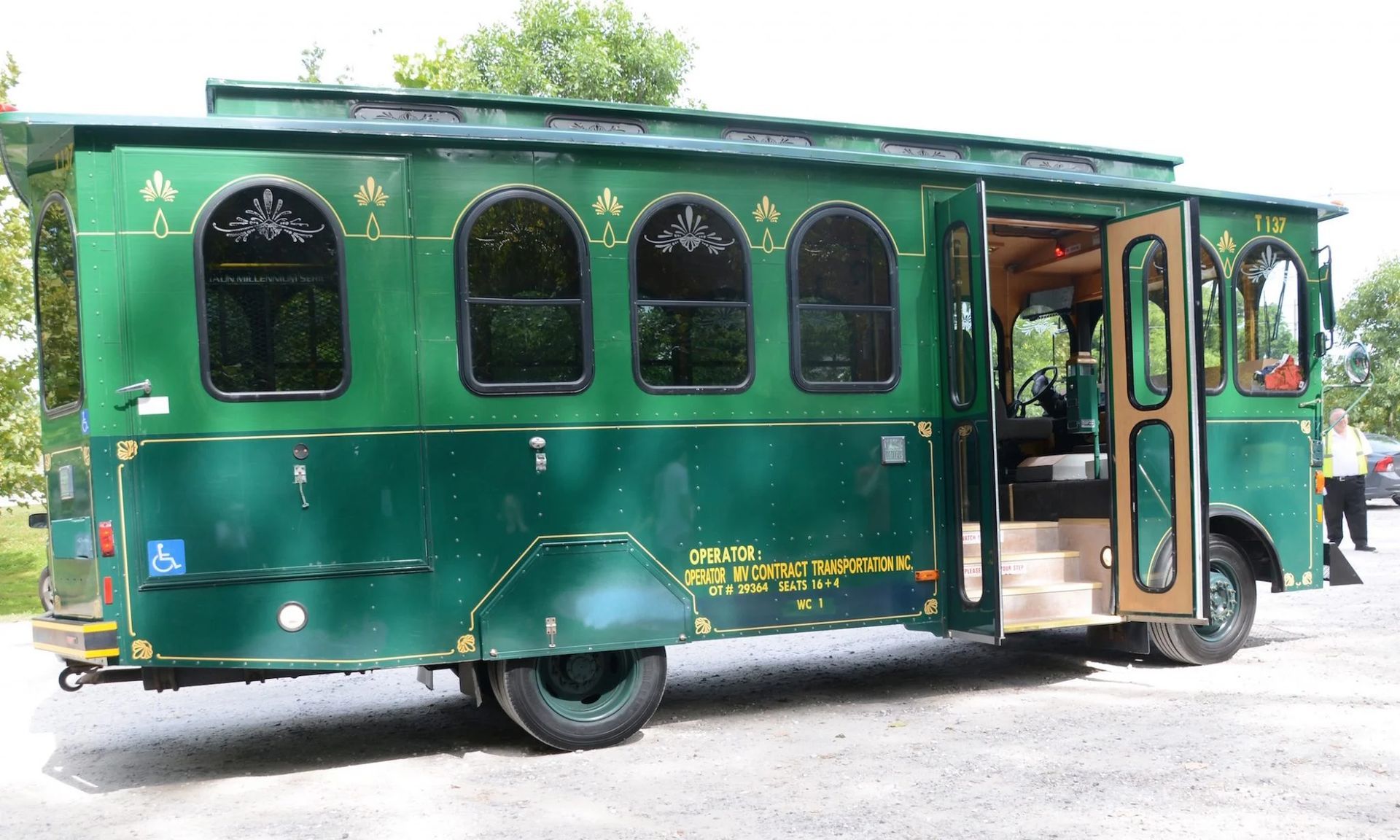 A green bus with the door open is parked on the side of the road