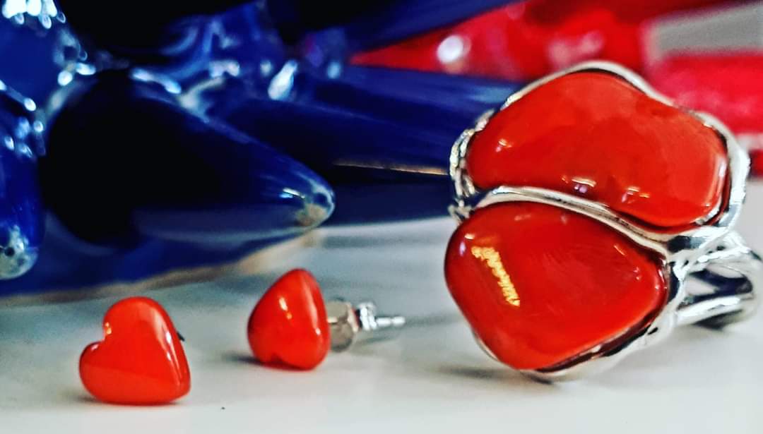 paio di orecchini rossi a forma di cuore e un anello.