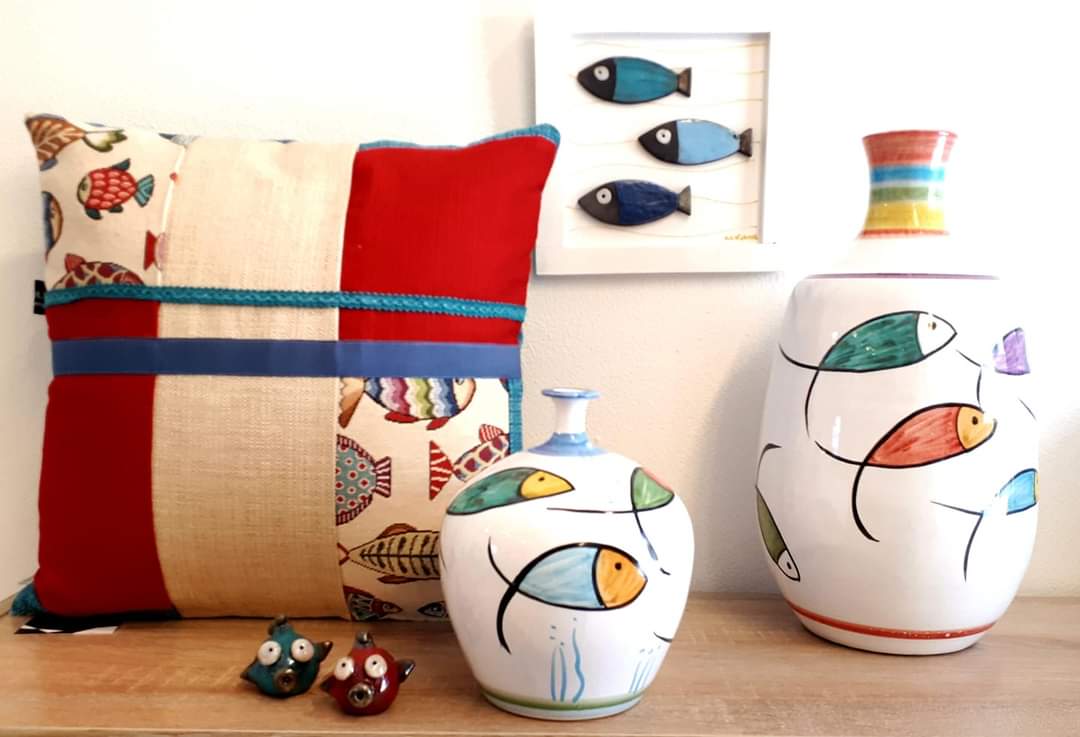 Su un tavolo ci sono tre vasi con pesci dipinti sopra