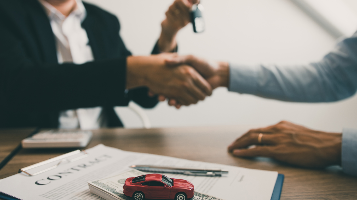 A man is shaking hands with a woman while holding a car key.