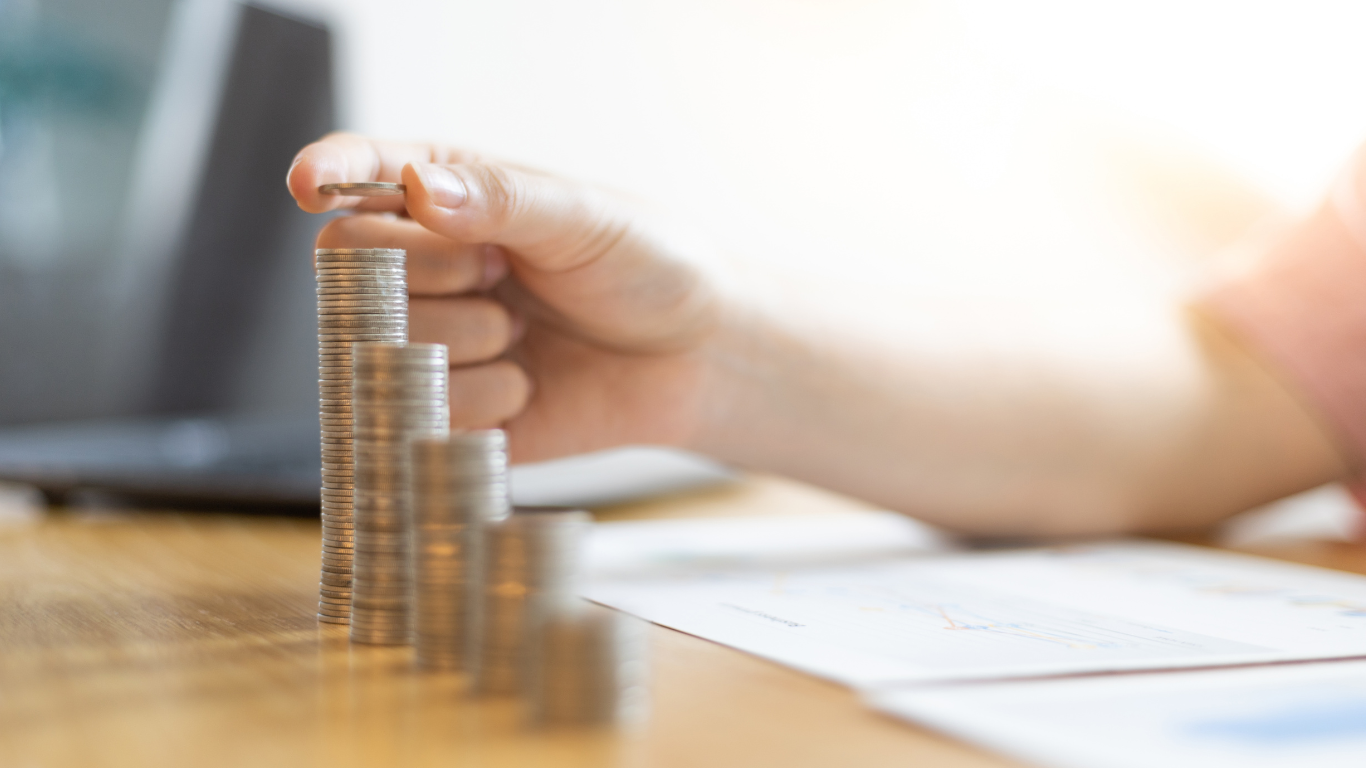 A person is stacking coins on top of each other on a table.