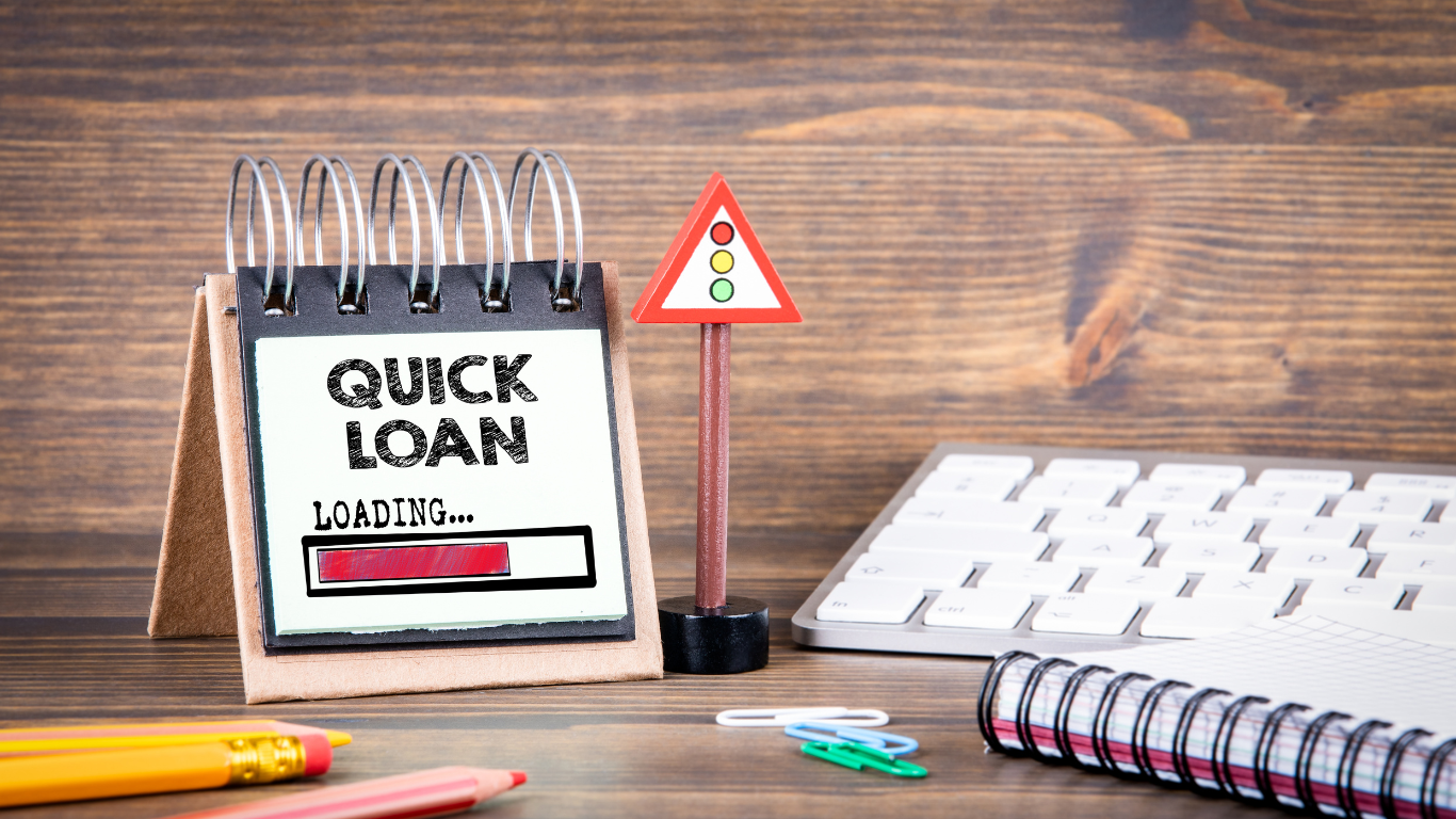 A calendar with the words `` quick loan '' written on it is sitting on a wooden desk next to a keyboard.