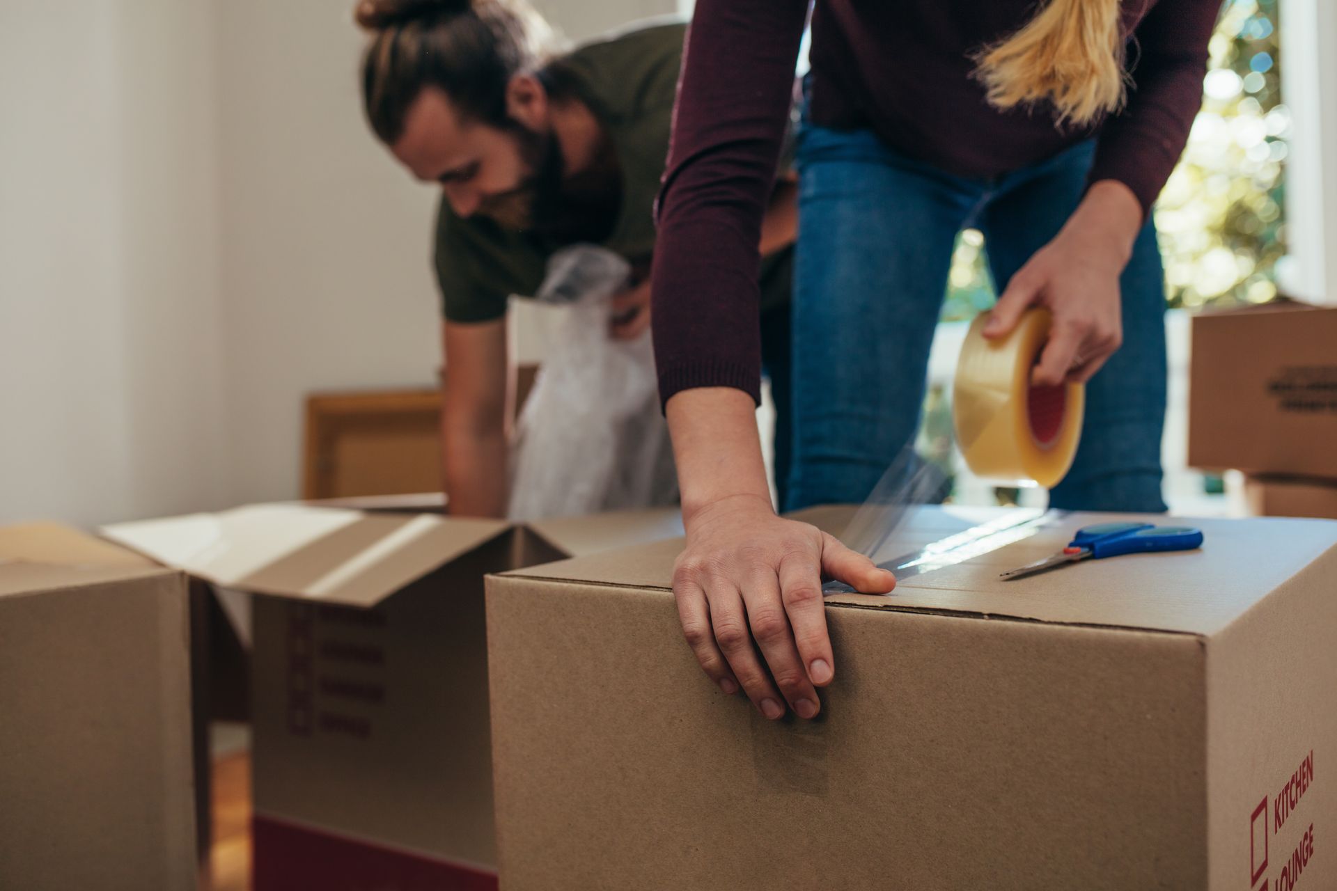 Close-up of a woman applying adhesive tape on a packing box.