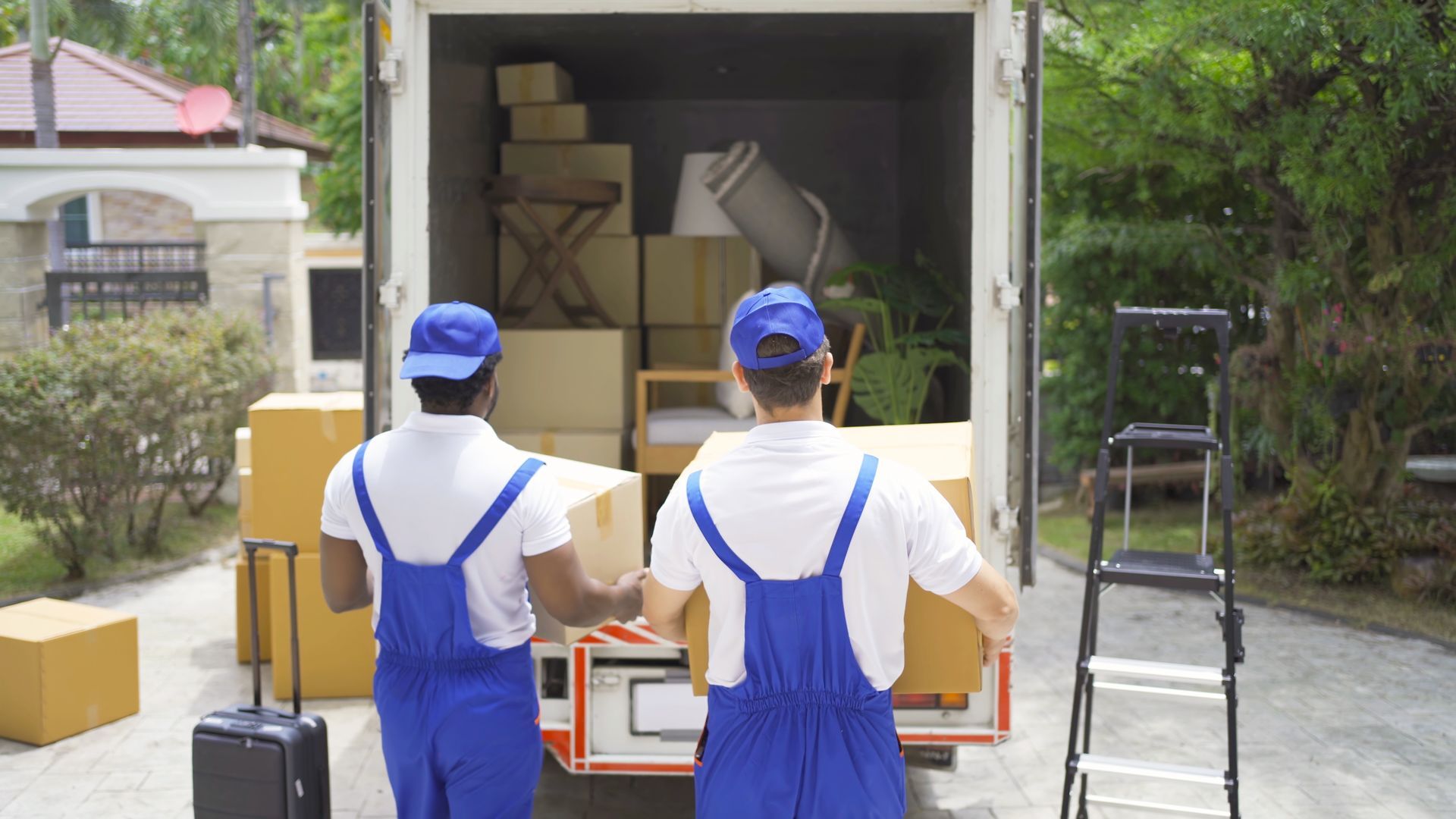Movers team of employee workers in uniform delivering boxes from moving truck for customers.
