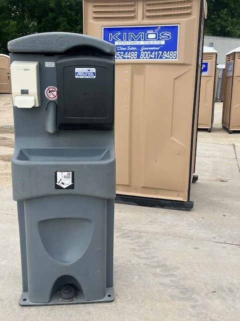 A man is lifting a portable toilet out of a truck.
