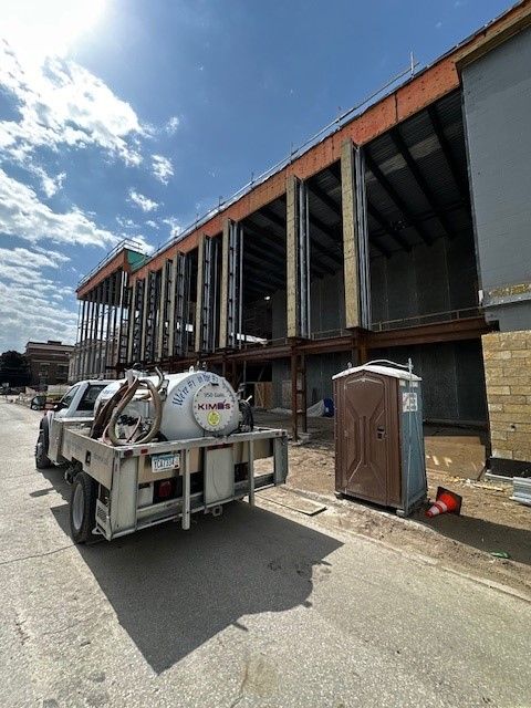 A portable toilet is sitting in front of a house under construction