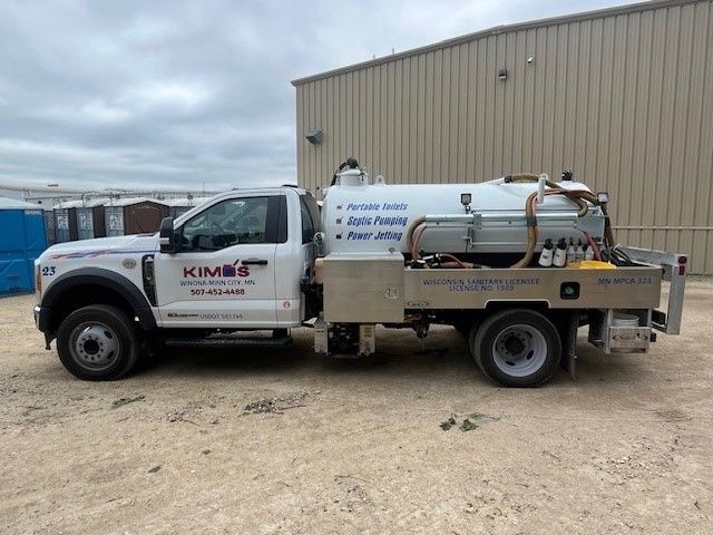 A portable toilet is attached to the back of a truck.