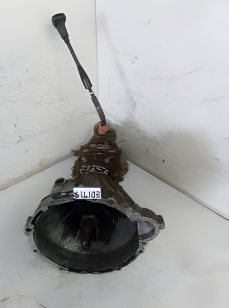 Mahindra Scorpio gearbox with gear lever attached, positioned upright against a white workshop wall.