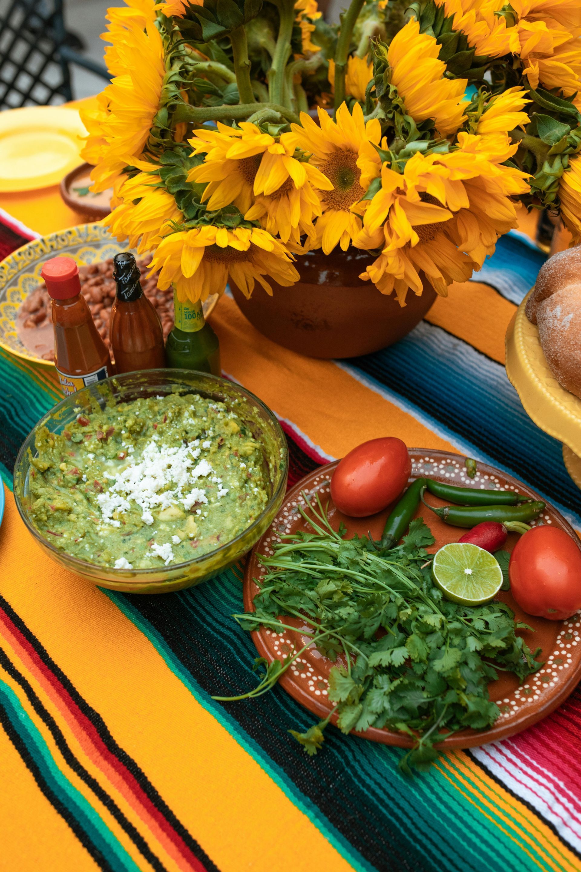 A table topped with plates of food and a vase of sunflowers.