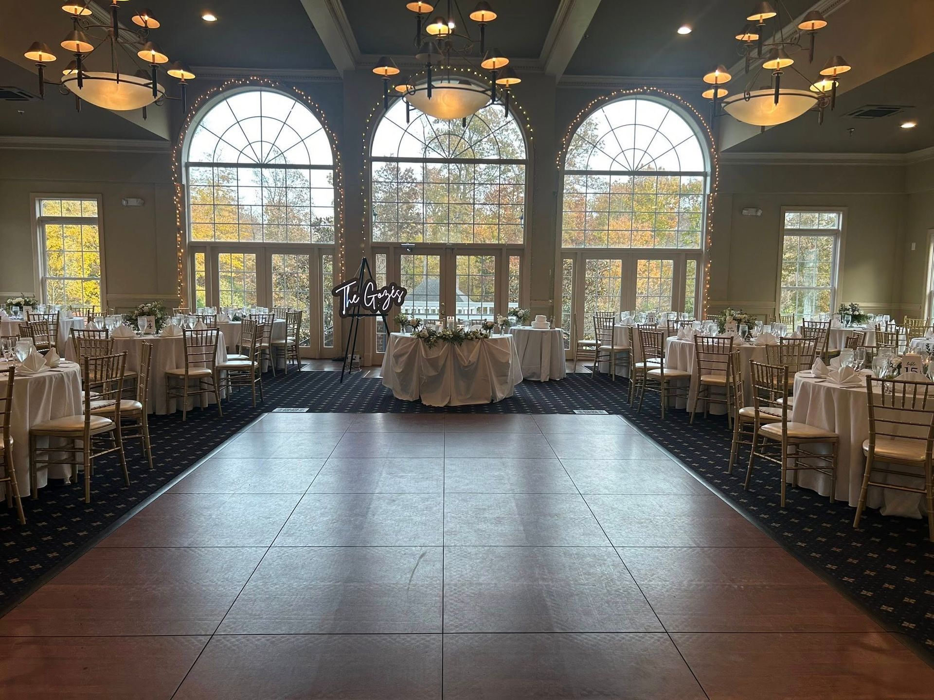 Ballroom with round tables set for an event, large windows, and a dance floor.