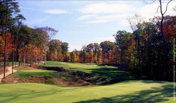 Golf course fairway in autumn. Lush green grass, colorful trees, blue sky.